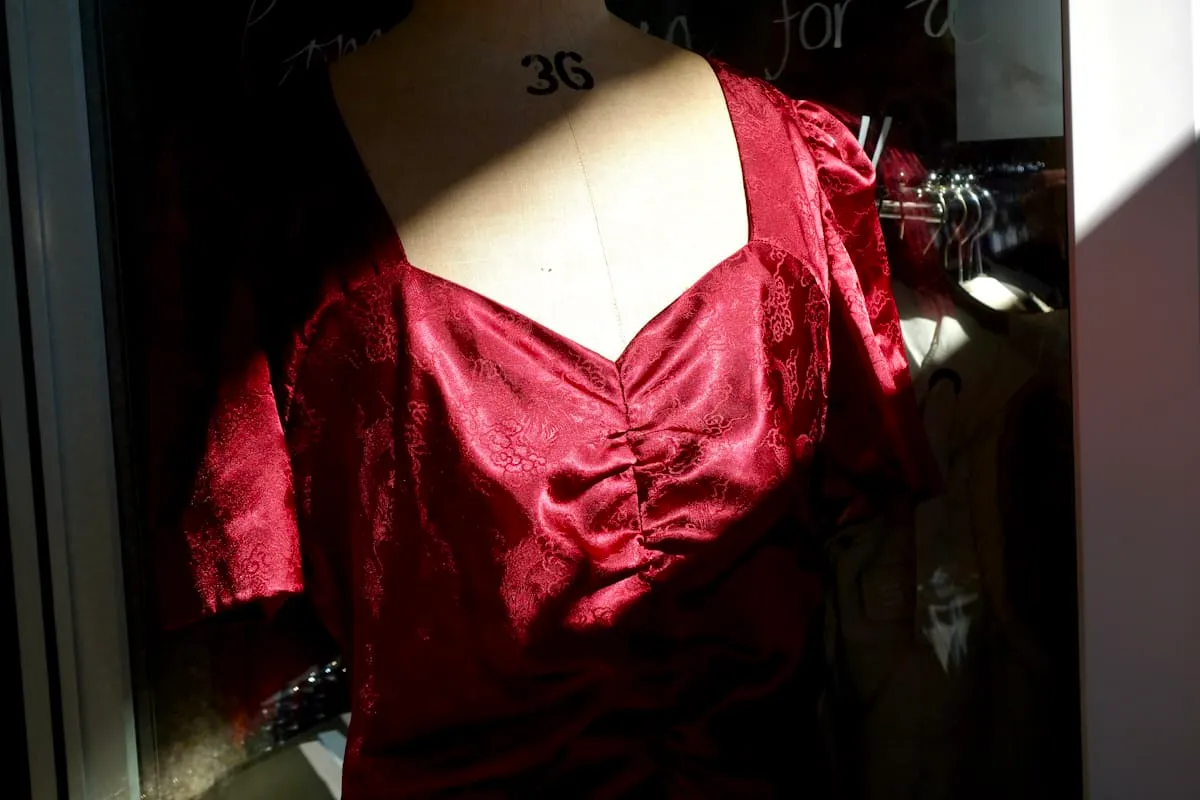 Burgundy satin bodice displayed on a dress form